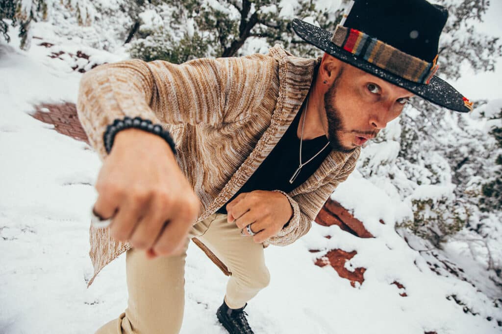 Close-up of Jaramy Wilson playfully lunging in a patterned cardigan and hat in the snow