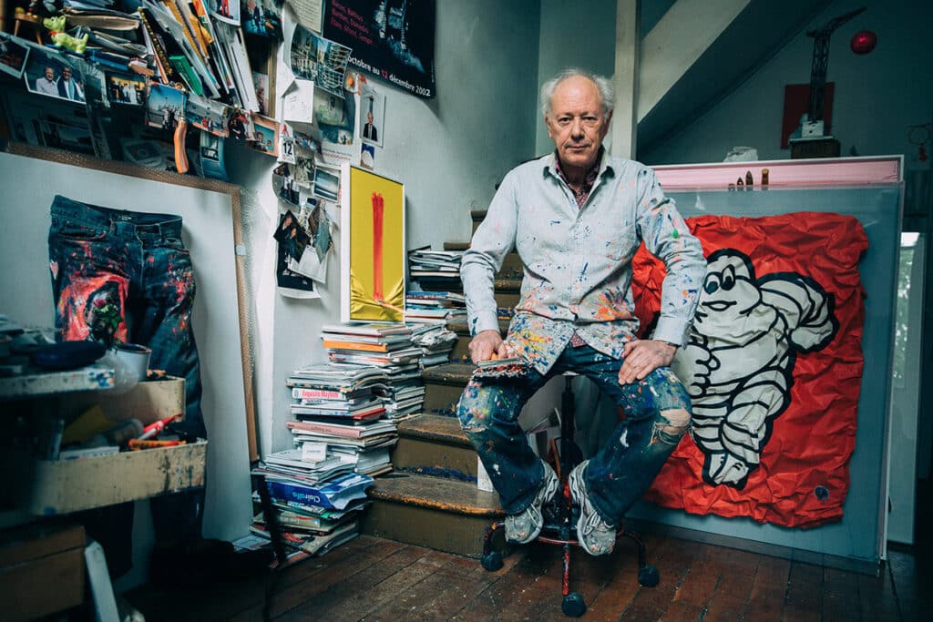 Renowned artist in a paint-covered studio, surrounded by creative tools and visual artifacts, embodying authentic identity through environment and self-expression