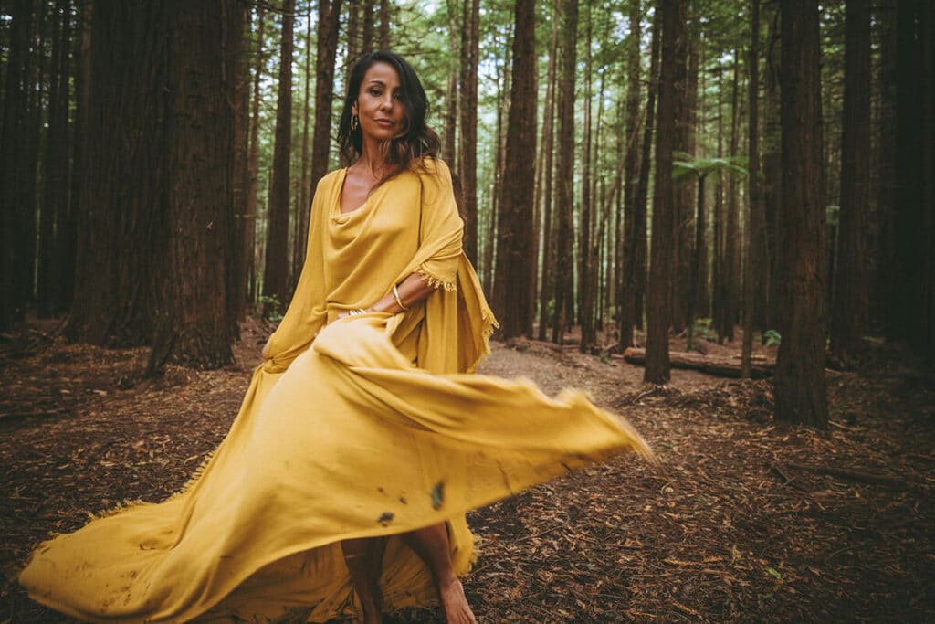 Nicky Clinch standing in a misty forest at dawn, wrapped in a shawl—evoking spiritual presence and personal transformation