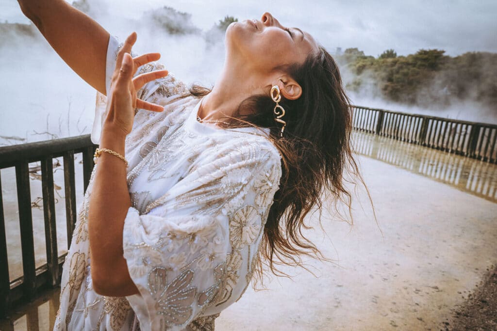 Nicky dancing barefoot in natural light on a rocky ledge, flowing dress in motion—capturing liberated feminine energy