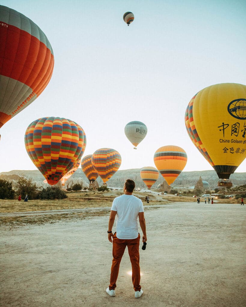 Lewis Howes walking through Cappadocia with hot air balloons rising behind him — symbolizing expansion and visual identity elevation