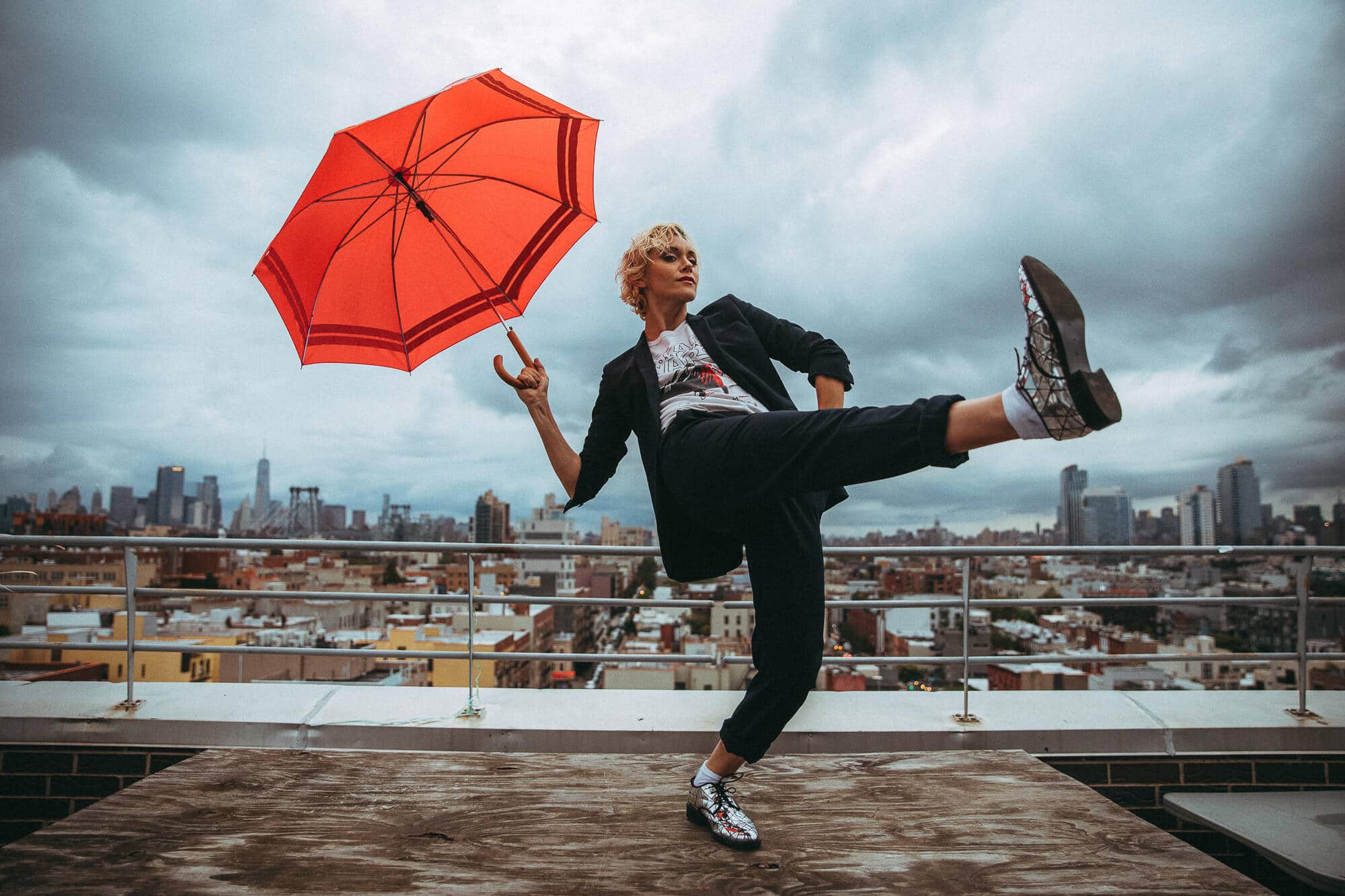 Alyson Stoner dancing with a red umbrella on a Brooklyn rooftop during a personal brand photoshoot by Nick Onken