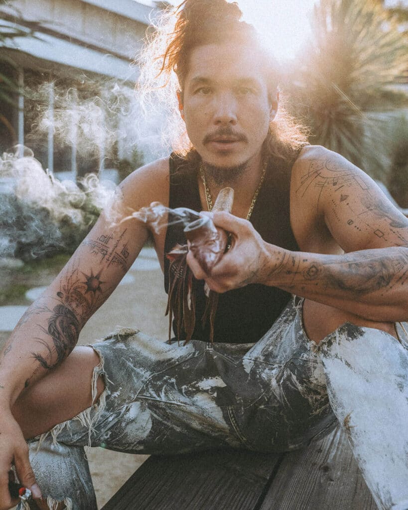 Nick Onken holding ceremonial sage with new dragon and lightcode tattoo, captured in golden hour as a symbol of creative transformation and personal power