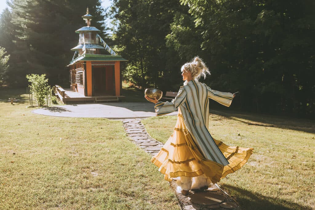 Spiritual entrepreneur twirling in golden light near a temple during a personal brand photoshoot with Nick Onken