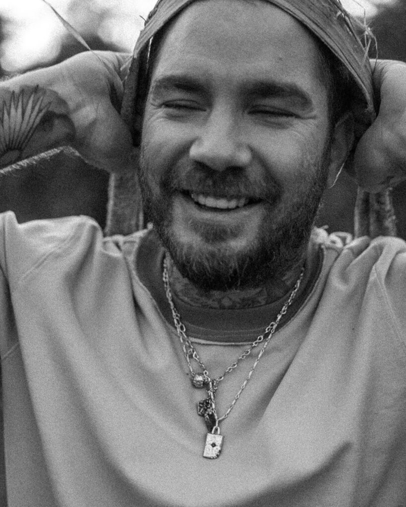 Black-and-white portrait of tattoo artist Balazs smiling with eyes closed, capturing his creative joy and spiritual energy