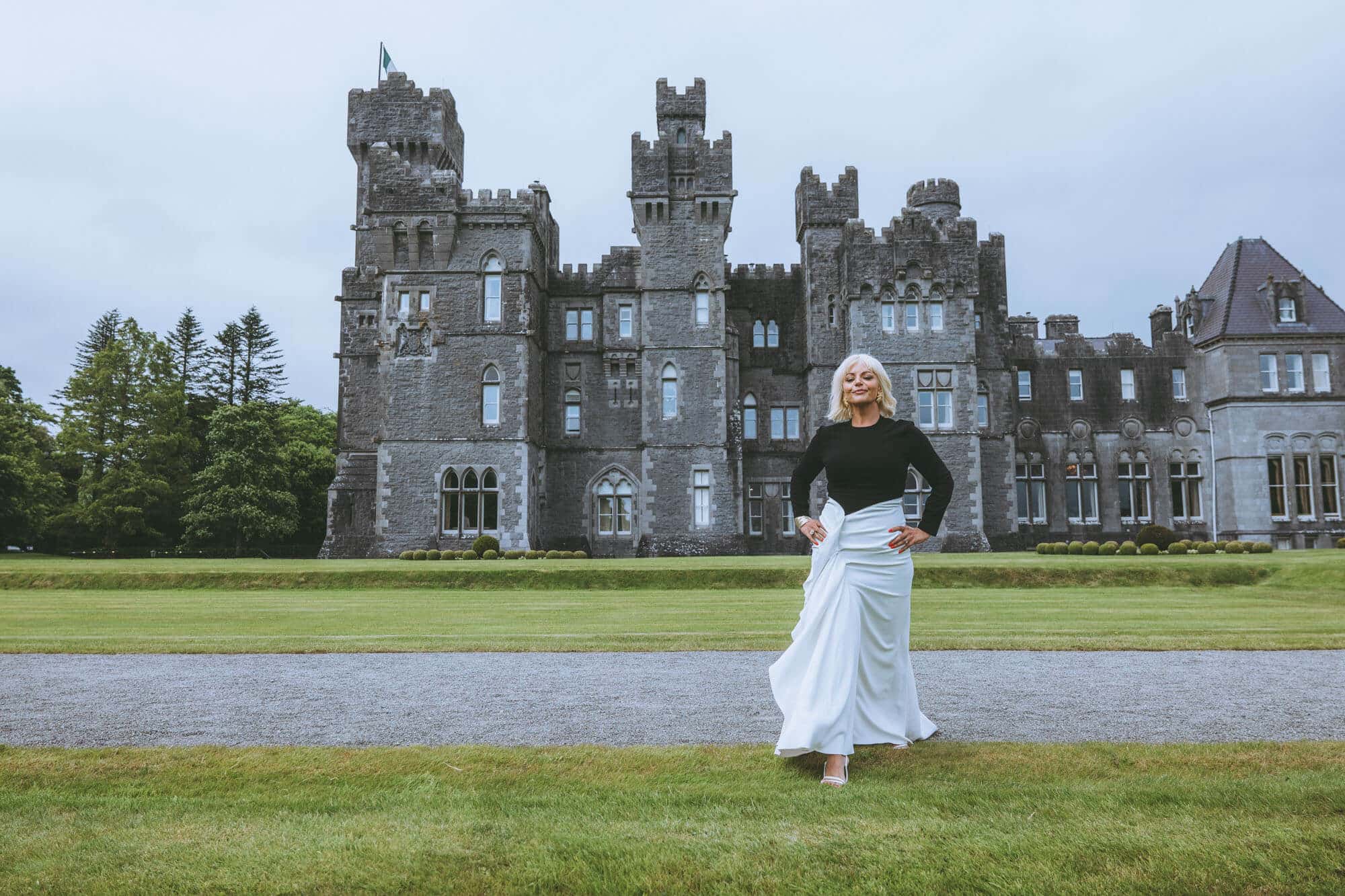 Editorial portrait of Caoimhe Harrison standing in the stone corridor of an ancient Irish castle during an Elevated Realism shoot