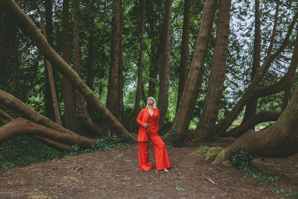 Caoimhe Harrison walking with intention through wild terrain, cloak flowing behind her in motion