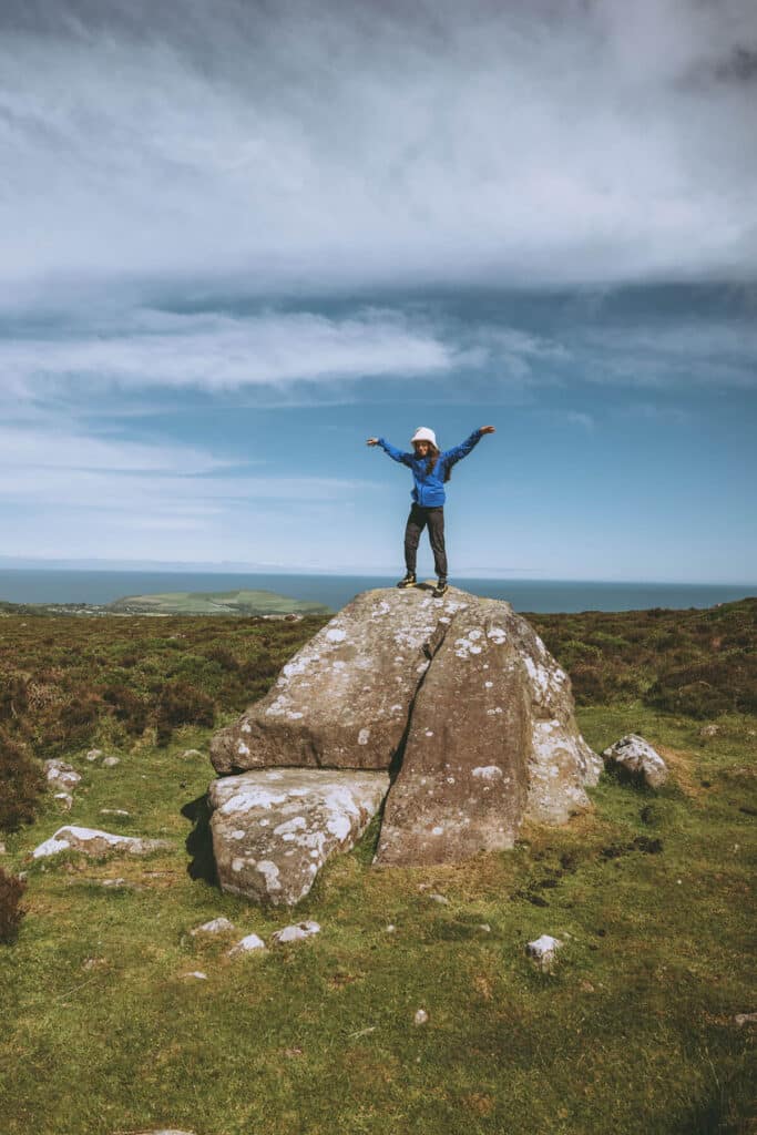 Emma Reicher doing qigong on rocks in vast Wales landscape during brand photography